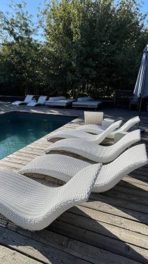 Otel havuzunun yanındaki güneş pansiyonları. Yüzme havuzunun yanında boş güneş pansiyonları. Beyaz plastik güneş pansiyonları açık mavi yüzme havuzunun yanındaki açık hava oteli avlusunda. Yaz tatili kavramı
