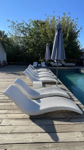 Otel havuzunun yanındaki güneş pansiyonları. Yüzme havuzunun yanında boş güneş pansiyonları. Beyaz plastik güneş pansiyonları açık mavi yüzme havuzunun yanındaki açık hava oteli avlusunda. Yaz tatili kavramı