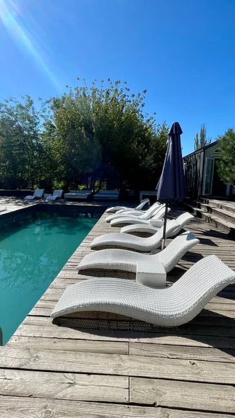 Otel havuzunun yanındaki güneş pansiyonları. Yüzme havuzunun yanında boş güneş pansiyonları. Beyaz plastik güneş pansiyonları açık mavi yüzme havuzunun yanındaki açık hava oteli avlusunda. Yaz tatili kavramı