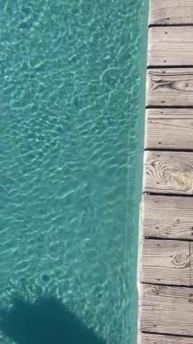 Yüzme havuzu yüzeyinde güneş ışığı yansıması olan dalgalı mavi suyun yakın görüntüsü. Mavi yüzme havuzu su yüzeyi ve dalgalı arka plan. Yüzme havuzu teması. Havuzda su yüzeyi