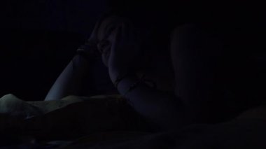 Sevimli ergen Smartphone kullanarak ve geceleri, yatakta yatarken rahat ve bıkkın