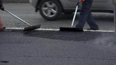 İşçilerin sıcak asfalt bir sokak yol inşaat işçileri ile kürek koruyucu üniformalı koyarsın. Sıcak günde çalışma.