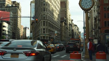 NEW YORK CITY - CIRCA 2019 - New York 'un ikonik Flatiron binasının önünden geçen trafik. Flatiron binası şimdiye kadar inşa edilen ilk gökdelenlerden biri olarak kabul ediliyor.