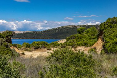 Kum tepeleri, kaya oluşumları ve Hırvatistan 'ın Rab adasındaki Ciganka doğabilimci plajına giden yol.