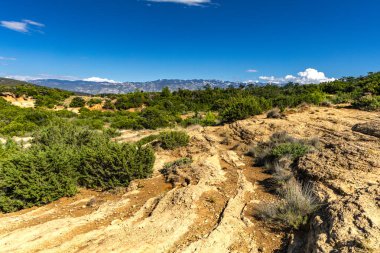 Kum tepeleri, kaya oluşumları ve Hırvatistan 'ın Rab adasındaki Ciganka doğabilimci plajına giden yol.