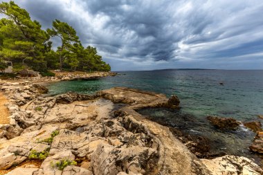 Tara Sahili, Rab, Adriyatik Denizi kıyısında güneş şemsiyeleri, bulutlu, tehditkar gökyüzü, gök mavisi su