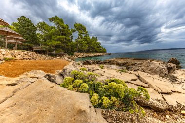 Tara Sahili, Rab, Adriyatik Denizi kıyısında güneş şemsiyeleri, bulutlu, tehditkar gökyüzü, gök mavisi su