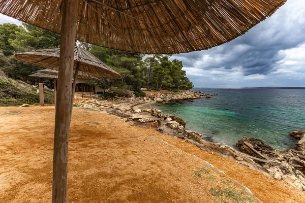 Tara Sahili, Rab, Adriyatik Denizi kıyısında güneş şemsiyeleri, bulutlu, tehditkar gökyüzü, gök mavisi su