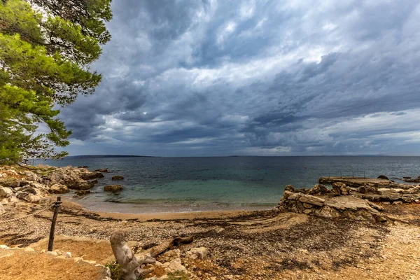 Tara Sahili, Rab, Adriyatik Denizi kıyısında güneş şemsiyeleri, bulutlu, tehditkar gökyüzü, gök mavisi su