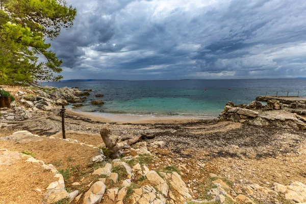 Tara Sahili, Rab, Adriyatik Denizi kıyısında güneş şemsiyeleri, bulutlu, tehditkar gökyüzü, gök mavisi su