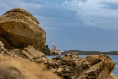 Rab kasabasında çan kulesi olan tarihi kule, yüksek kilise kulesinin uzak bir görüntüsü.