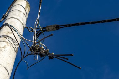 Kesilmiş bir elektrik hattı, kopmuş bir elektrik hattı, mavi gökyüzü arka planına karşı elektrik direğinin kablolarını kesmiş.
