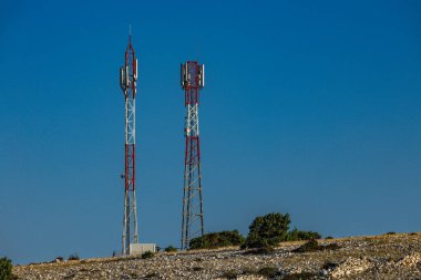 Ra adasındaki Lopar kasabasının yukarısındaki bir tepenin üzerinde televizyon ve radyo sinyalleri yayınlamak için iki uzun telekomünikasyon anten direği.