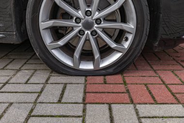 Otoparkta park etmiş bir yolcu aracının lastiği patlamış, arabanın lastiğini değiştirmeye hazırlanıyor.