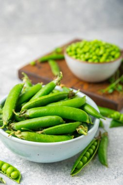 Ahşap zemin üzerinde yeşil bezelyeler olan taze bezelye kabukları. Tatlı yeşil bezelyeler. Yeşil bezelye fasulyesi sebzesi. Vejetaryen. Sağlıklı sebze. Boşluğu kopyala