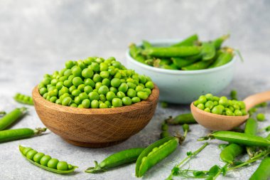 Ahşap zemin üzerinde yeşil bezelyeler olan taze bezelye kabukları. Tatlı yeşil bezelyeler. Yeşil bezelye fasulyesi sebzesi. Vejetaryen. Sağlıklı sebze. Boşluğu kopyala