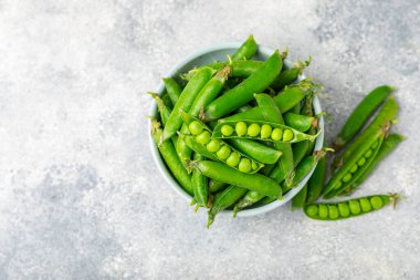 Ahşap zemin üzerinde yeşil bezelyeler olan taze bezelye kabukları. Tatlı yeşil bezelyeler. Yeşil bezelye fasulyesi sebzesi. Vejetaryen. Sağlıklı sebze. Boşluğu kopyala