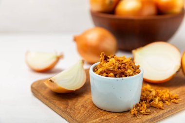 Tahta bir masada kasede kızarmış soğan. Kızarmış soğan. Bulaşık çeşnisi. Baharatlar. Salata sosu. Mesaj için yer var. Boşluğu kopyala