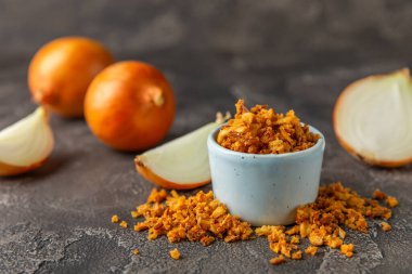 Tahta bir masada kasede kızarmış soğan. Kızarmış soğan. Bulaşık çeşnisi. Baharatlar. Salata sosu. Mesaj için yer var. Boşluğu kopyala