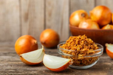 Tahta bir masada kasede kızarmış soğan. Kızarmış soğan. Bulaşık çeşnisi. Baharatlar. Salata sosu. Mesaj için yer var. Boşluğu kopyala