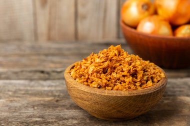 Tahta bir masada kasede kızarmış soğan. Kızarmış soğan. Bulaşık çeşnisi. Baharatlar. Salata sosu. Mesaj için yer var. Boşluğu kopyala