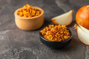 Tahta bir masada kasede kızarmış soğan. Kızarmış soğan. Bulaşık çeşnisi. Baharatlar. Salata sosu. Mesaj için yer var. Boşluğu kopyala