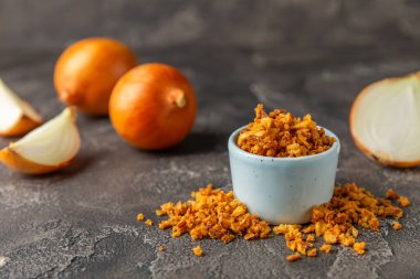 Tahta bir masada kasede kızarmış soğan. Kızarmış soğan. Bulaşık çeşnisi. Baharatlar. Salata sosu. Mesaj için yer var. Boşluğu kopyala