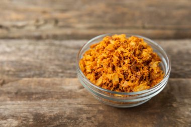 Tahta bir masada kasede kızarmış soğan. Kızarmış soğan. Bulaşık çeşnisi. Baharatlar. Salata sosu. Mesaj için yer var. Boşluğu kopyala