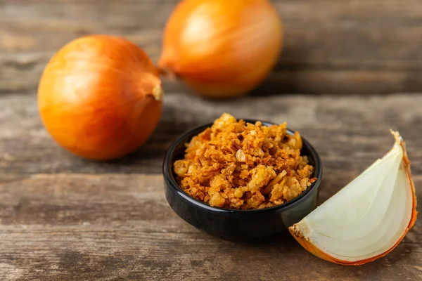 Tahta bir masada kasede kızarmış soğan. Kızarmış soğan. Bulaşık çeşnisi. Baharatlar. Salata sosu. Mesaj için yer var. Boşluğu kopyala