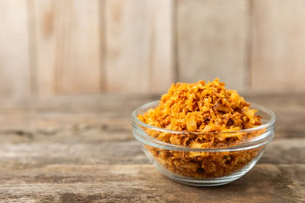 Tahta bir masada kasede kızarmış soğan. Kızarmış soğan. Bulaşık çeşnisi. Baharatlar. Salata sosu. Mesaj için yer var. Boşluğu kopyala