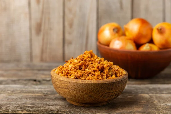 Tahta bir masada kasede kızarmış soğan. Kızarmış soğan. Bulaşık çeşnisi. Baharatlar. Salata sosu. Mesaj için yer var. Boşluğu kopyala