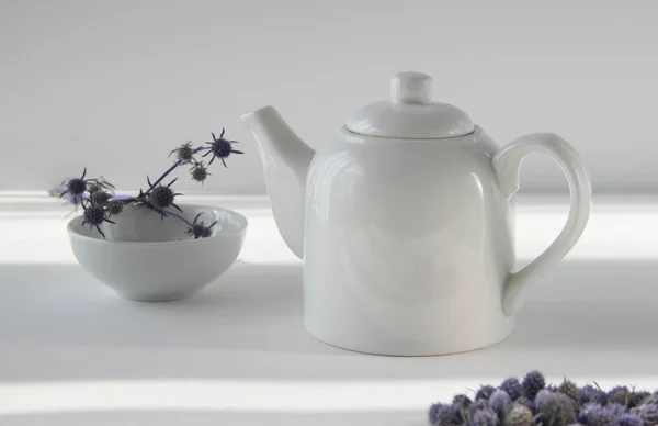 Beyaz arkaplanda çiçekli beyaz çaydanlık.