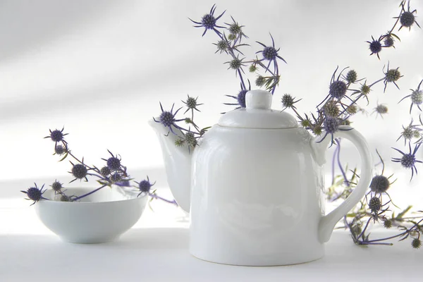 Beyaz arkaplanda çiçekli beyaz çaydanlık.