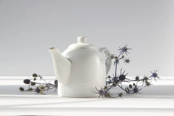 Beyaz arkaplanda çiçekli beyaz çaydanlık.