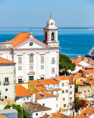 Lizbon, Portekiz. Kilisesi ve çan kulesi olan güzel bir şehir manzarası. Binalar beyaz ve kırmızı, gökyüzü mavi.
