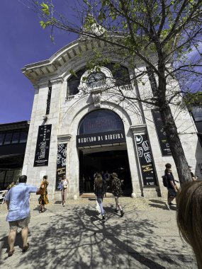 Bir grup insan önünde büyük bir saatle bir binaya giriyor. Binanın adı Museo de Arte Moderno