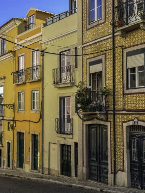 Sarı ve bronzlaşmış balkonlu binalar ve yeşil kapılar. Binalar eski ve kırsal bir cazibesi var.