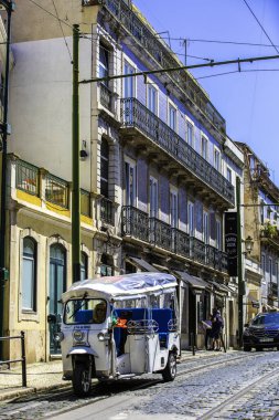 Lizbon, Portekiz - Mavi ve Beyaz Tuk bir binanın önündeki kaldırım taşı caddesinde park halinde.