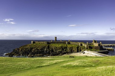 Peel Island of Man 08.15.2023 Şatosu ve plajı olan güzel, sakin bir manzara. Kale yemyeşil bir tarla ile çevrilidir ve plaj uzaktan görülebilir. Gökyüzü açık ve güneş parıldıyor Man Adası -
