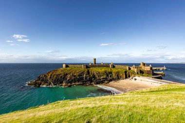 Peel Isle of Man 08.15.2023 Uzaktaki şatosu olan güzel bir sahil. Gökyüzü berrak ve su sakin Man Adası -