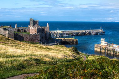 Peel Isle of Man 08.15.2023 Arka planda şatosu olan güzel bir liman manzarası. Kale eski ve bir sürü tarihi var. Liman teknelerle dolu ve su sakin. Manzara huzurlu ve huzurlu Man Adası -