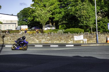 Douglas, Man Adası 08.05.2023 Adam bir caddede motosiklet sürüyor. Motosiklet mavi ve üzerinde 9 numara var. Adam kask takıyor ve Man Adası 'nın ortasında at sürüyor. -