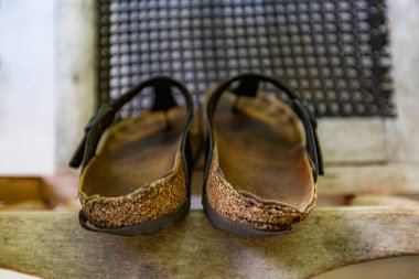 Ayakkabılar yıpranmış ve kahverengi tabanlı. Onlar ahşap bir yüzeyde oturuyorlar. Ayakkabılar kullanılmıyor.