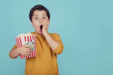 mavi arka plan üzerinde patlamış mısır ile sürpriz çocuk