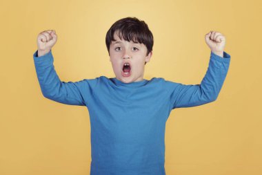 Eller havaya sarı arka planda çığlık ile mutlu çocuk