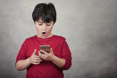 gri arka plan üzerinde bir cep telefonu ile sürpriz çocuk