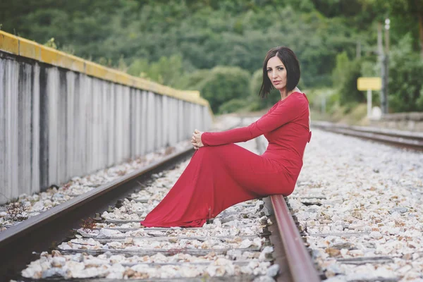 Tren rayları üzerinde oturan dalgın kadın