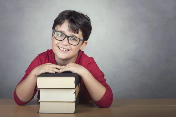 Улыбающийся Маленький Мальчик Опирающийся Книги Столе Сером Фоне — стоковое фото