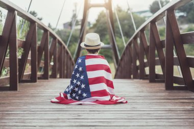 Üzgün çocuk ahşap köprü üzerinde Amerika Birleşik Devletleri bayrağı