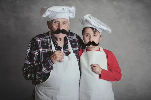 Grandfather With Grandson with cook hat and mustache on gray background